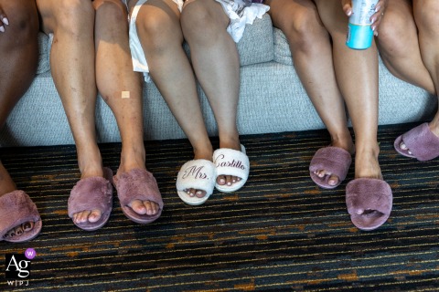   At Doubletree San Diego Bayside in San Diego, California, the bride relaxes on a couch with her bridesmaids, all wearing slippers in a cozy and fun pre-ceremony detail shot.