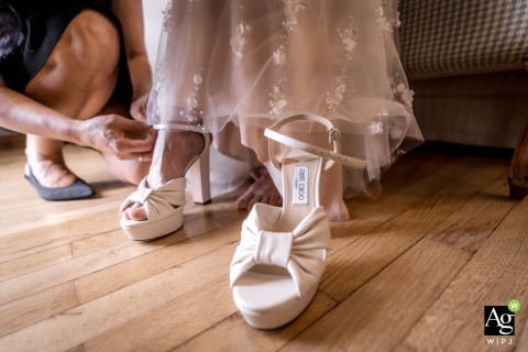 At Hotel Villa Cipriani in Asolo, Italy, a close-up captures a bridesmaid gently helping the bride slip on her elegant wedding shoes, blending grace and anticipation.