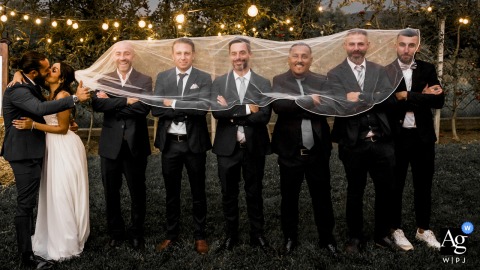 Couple Kiss As Groomsmen Wait At A Modo Mio In Ovada, Underscoring The Blend Of Excitement And Serenity In Ovada at A modo Mio, the couple is shown kissing while groomsmen are waiting, reflecting the excitement and serenity that fills the start of the celebration.