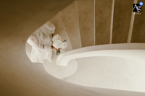 Bride’s Figure Poised On The Staircase Is Highlighted By Artistic Assessment Of Light And Shadow In Montpellier On the staircase at the bride’s Montpellier home, an image highlights her poised figure, with shadows and light creating an artistic portrait full of anticipation.