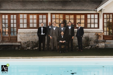 Groom Waits Poolside With Groomsmen And Friends At Isere Reception, Anticipation Grows The groom stands with his groomsmen and witnesses poolside, waiting for the bride at the reception space in Isere, anticipation and friendship filling this candid group portrait.