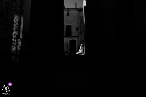 Along Rue De Calvisson In France, The Couple Walks Among Quaint Buildings Softly Lit By Natural Daylight The wedding couple walks together along Rue de Calvisson in France, their passage through the street framed by quaint buildings and the soft, natural light of the day.