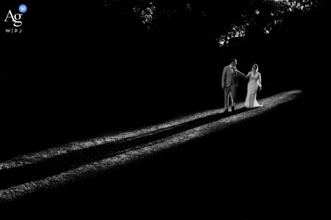 Newlyweds Walk Together Down The Sunlit Aisle At Château Bas d’Aumelas, The Historic Backdrop Grand And Picturesque Sunlight streams down the aisle at Château Bas d'Aumelas as the newlyweds walk together, the historic château offering a grand and picturesque backdrop.