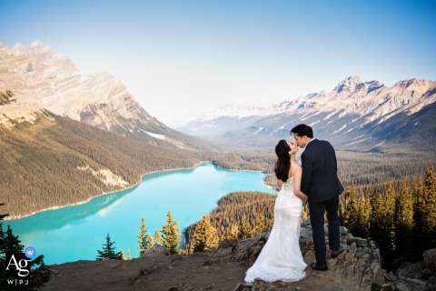  The bride and groom share a kiss by the striking turquoise waters of Peyto Lake, Canada, the remote mountain setting highlighting the beauty of their love.