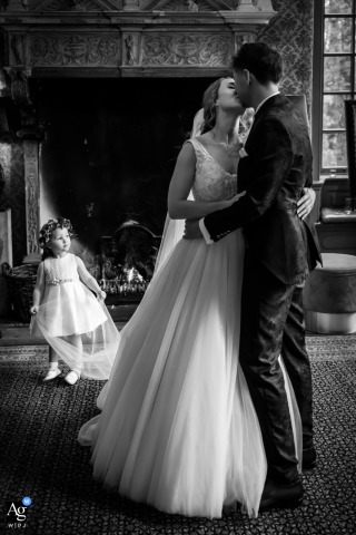 The Library At Kasteel Wijenburg In Echteld Hosts A Playful, Multi-Generational Portrait With The Couple And A Little Girl In the library at Kasteel Wijenburg in Echteld, the couple poses with the little girl playfully interacting with the veil, capturing a warm multi-generational portrait.