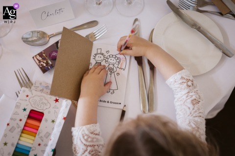 Creativity And Color Fill Hazlewood Castle In West Yorkshire Where A Young Guest Enjoys Arts And Crafts At The Reception At Hazlewood Castle in West Yorkshire, a young guest enjoys children's crafts, the reception space filled with color and creativity that add to the festive family atmosphere.