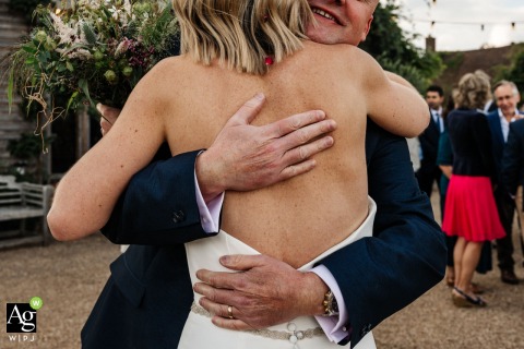 Bride Hugs Wedding Guest Affectionately At High Billinghurst Farm Venue In Surrey England A heartfelt hug between the bride and a guest is captured in detail at High Billinghurst Farm Wedding Venue in Surrey, England, showing the warmth of familial bonds.