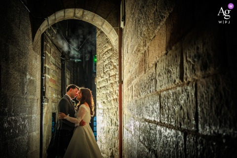 Bride And Groom Backlit By Flash In Narrow Lane Outside Ghillie Dhu Edinburgh In a narrow lane outside the venue Ghillie Dhu in Edinburgh, the bride and groom are dramatically backlit by off-camera flash, creating a striking nighttime portrait with urban character.