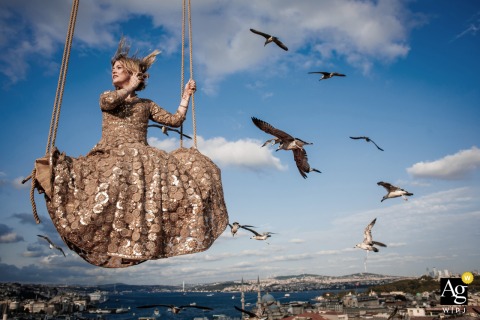 Bride Sits On Swing Framed Against Sweeping City Views In Suleymaniye Istanbul On a rooftop terrace in Suleymaniye, Istanbul, the bride sits on a swing, her figure framed against sweeping city views in a playful and elevated portrait.