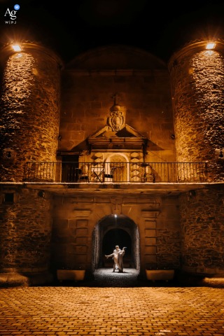 Couple Shares Dance Step Beneath Stone Arch At Chartreuse De Sainte Croix Loire Under the stone arch at Chartreuse de Sainte Croix en Jarez in the Loire, the couple shares a dance step, with historic architecture providing both structure and romance to the scene.