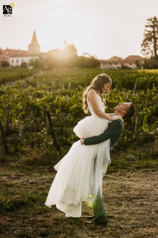 Couple Shares Relaxed Moment Among Vineyard Rows At Domaine Des Palais Loire Among grapevines at Domaine des Palais in Ambierle, Loire, the couple shares a relaxed interaction, surrounded by vineyard rows that impart a tranquil, scenic setting to their portrait.