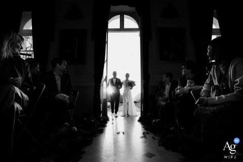 Bride Enters Ceremony On Father’s Arm At Sunset Château De Denonville France With a glorious sunset behind them at Château de Denonville, France, the bride steps into the ceremony on her father’s arm, her entrance enhanced by the soft light and outdoor ambiance.