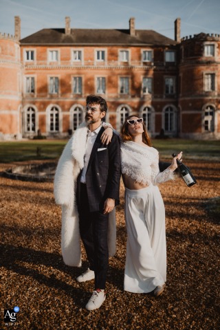 Newlyweds Strike Playful Pose Against Grand Château De Denonville Reception Castle At Château de Denonville, the newly married couple strike a playful pose, connecting with the whimsical image of a couple set against their grand reception castle.