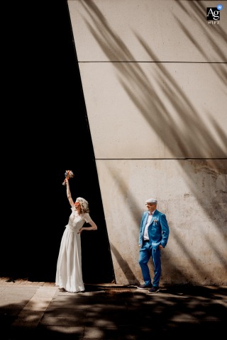 Newlyweds Share Playful Moment Against Striking High-Contrast Wall At Nantes City Hall After their civil ceremony at the City Hall of Nantes in France, the newlyweds enjoy a playful session together, contrasting brightly against a striking, high-contrast wall.