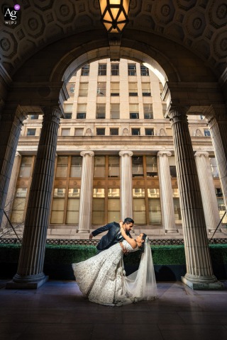 Couple Shares Dramatic Dip Beneath Grand Arches In Ballroom At The Ben Inside the Ballroom at the Ben in Philadelphia, the couple’s dramatic dip beneath grand arches combines elegance and devotion for a portrait that showcases both love and architectural beauty.