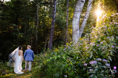   As the sun sets in Houlton, Maine, soft golden light streams through the woods, illuminating the couple’s walk together for a portrait infused with romance and natural beauty.