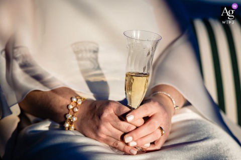   At her Bar Harbor elopement in Maine, the bride holds a champagne glass, with distinctive shadows falling across her gown to create a memorable detail from the celebration.