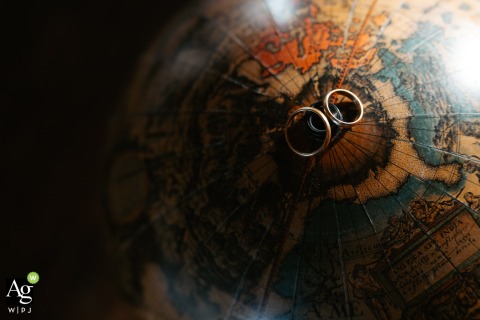 Two Wedding Rings Rest on Globe at Castello di Torre Alfina in Viterbo, Italy, Symbolizing Unity and Love At Castello di Torre Alfina in Viterbo, two wedding rings face each other atop a partially shadowed round spinning globe ball, symbolizing unity against a backdrop of subtle contrast and intrigue.