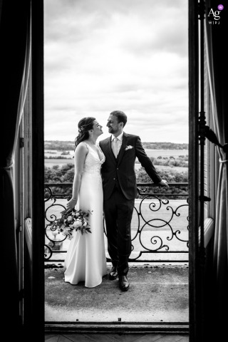   Relaxing on the balcony of Chateau de Dangu in Eure, France, the bride and groom recline side by side, taking a quiet bw session to themselves at the historic château.