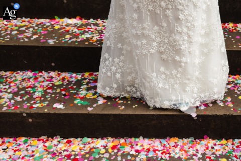   Bursts of colorful confetti surround a close-up of the bride’s dress outside Chelsea Town Hall, filling the frame with vibrant hues and a sense of festive celebration.