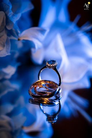 Elegant Wedding Rings Shining Against A Vivid Blue Background In Venezia Italy Wedding rings appear elegantly presented against a vivid blue background in Venezia, Italy, their metallic shine contrasting beautifully with the striking color beneath them.
