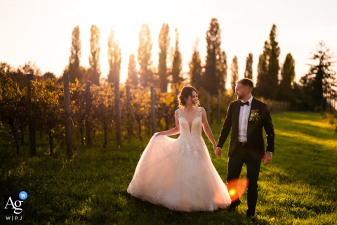 Bride And Groom Silhouettes Walking Against The Warm Sunset In Udine Italy As the sun sets over Udine, Italy, the bride and groom walk for a romantic portrait, their silhouettes softly illuminated against the warm colors of the evening sky.
