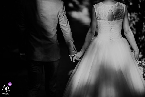 At the ceremony location in Budapest, Hungary, the bride and groom walk hand in hand into their new chapter, captured in a dreamy black-and-white image where dappled light and their quiet stride create a timeless, intimate portrait.