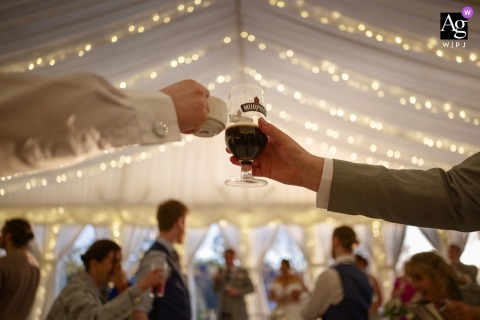 At Clonabreany House, Ireland, guests raise cups of tea in a cheerful toast during the wedding speeches, creating a warm and distinctly personal celebration filled with smiles and shared tradition.