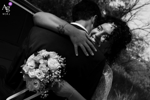 At Corte Feniletto in Quingentole, Mantova, Italy, the bride suddenly wraps the groom in an embrace, captured from an extremely close viewpoint with a dynamic diagonal composition that heightens the spontaneity and emotion of the moment.