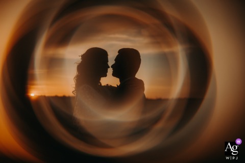 At Domaine de la Perdrière in France, the bride and groom share a sunset embrace, their silhouettes framed within a glowing circular composition that transforms the fading light into a striking and romantic wedding portrait.