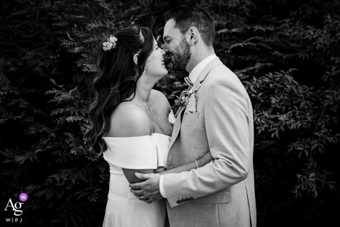 At Domaine des Templiers in France, the bride and groom share a joyful nose-to-nose embrace in a black-and-white portrait, their broad smiles and close connection standing out beautifully against a backdrop of dense, textured foliage.