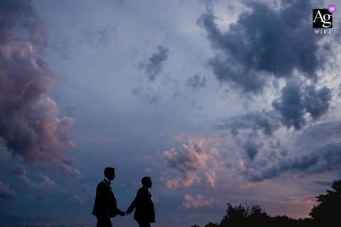 At Val de Caratel in Louisfert, Loire-Atlantique, France, the couple walk hand in hand beneath a blue hour sky painted with soft shades of blue and pink, creating a romantic portrait filled with color and quiet elegance.