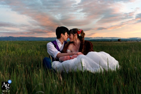 At Big Yellow Barn in Belgrade, Montana, the bride and groom sit together in a quiet field at sunset, creating a relaxed and intimate portrait surrounded by the warm glow of the evening countryside.