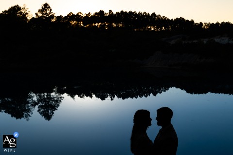 At Château de la Pouyade in Charente, France, the bride and groom are photographed in silhouette beside the river, creating a timeless portrait defined by elegant shapes and soft natural light.