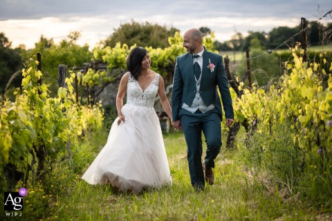 Rolling Vineyards Surround The Couple At Le Clos Vernay In Isère, France During Their Portrait Session At Le Clos Vernay in Isère, France, the bride and groom wander through the surrounding vineyards during their portrait session, creating timeless images framed by rolling vines and the beauty of the countryside.