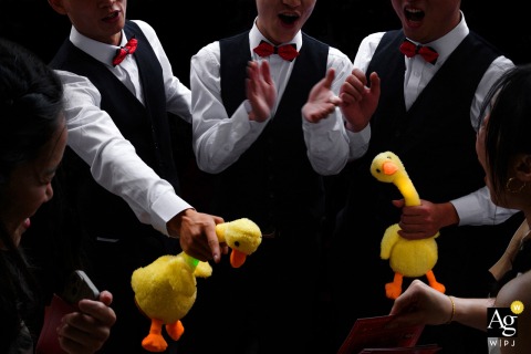 At the ceremony venue in Zhanjiang, Guangdong, China, the groomsmen and bridesmaids take part in a playful duck-themed wedding game, with the groomsmen's humorous attempts to hold the duck creating a lively and memorable moment.