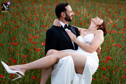 Vibrant Poppy Fields Surround The Couple During Their Portrait Session In Paladru, Isère, France In Paladru, Isère, France, the bride and groom share a quiet, intimate portrait session together in the middle of a vibrant poppy field, surrounded by the rich colors and natural beauty of the countryside.