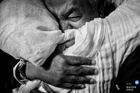 Close-up black and white photo of a man hugging the bride by a Charleston, SC wedding photographer.