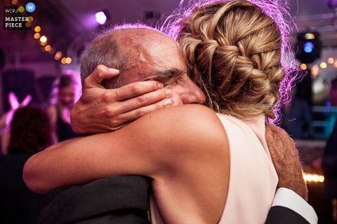 Photo of the bride hugging a man during the reception by a Paris, France wedding photographer.