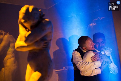Photo of a man hugging another from behind next to a statue by a San Francisco, CA wedding photographer.