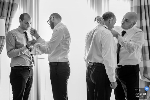 Black and white photo of the groomsmen getting ready for the ceremony by a Calabria wedding photographer.