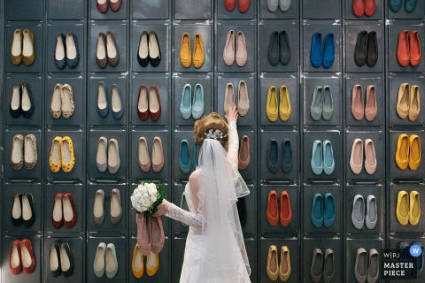 Een bruid observeert een muur met veelkleurige schoenen op deze foto van een trouwfotograaf uit Rome.