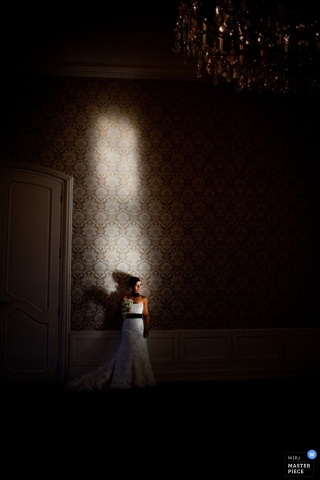 Vienna wedding photo portrait of the bride standing in a dark room while light from the window lights up her face