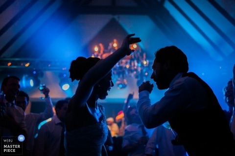 Paraná wedding photographer captured this photo of the bride and groom dancing as blue lights shine behind them