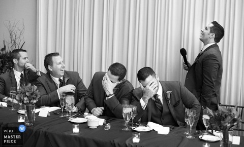 Chicago wedding photographer captured this black and white photo of the groomsmen reacting to the best mans hilarious speech at the reception