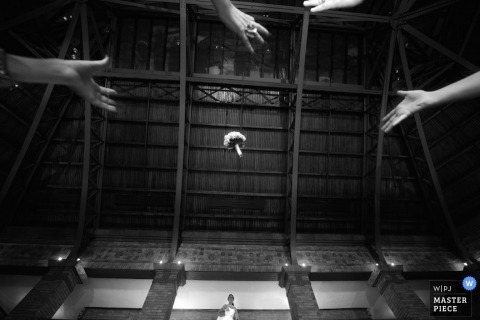 	Chicago wedding photographer captured this black and white photo of wedding guests hands reaching above the camera to catch the bouquet 