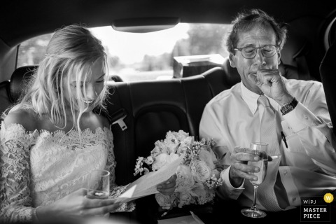 Atlanta wedding photographer captured this black and white photo of the bride riding in the car with her father on the way to the ceremony, smiling as she reads a letter and her bouquet rests beside her Atlanta wedding photographer captured this black and white photo of the bride riding in the car with her father on the way to the ceremony, smiling as she reads a letter and her bouquet rests beside her
