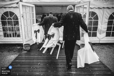 Photo by: <a href="https://www.wpja.com/contests/2015-q3-photography-contest/weather/1683516">Simon Cassanas - Paris Paris groomsmen moving chairs inside in the rain - France wedding photojournalism