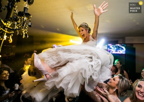 Santa Catarina bride getting held up by guests on the dance floor at the reception - Brazil wedding photojournalism