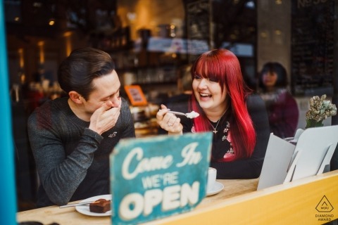 UK Engagement Photographer. Coffee shop couple shares a bite.